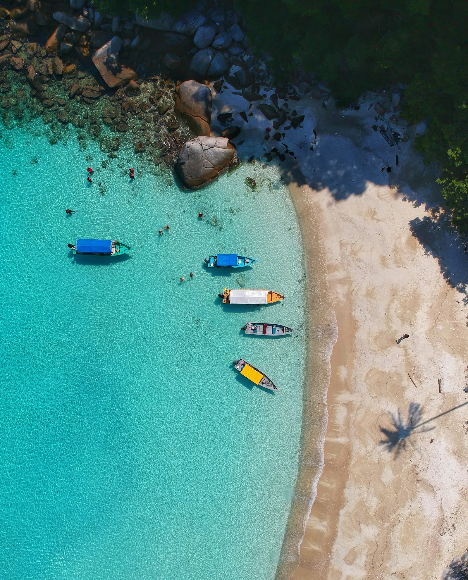 An aerial view of a turquoise bay with small boats, the kind of single frame that reads as a whole place at a glance