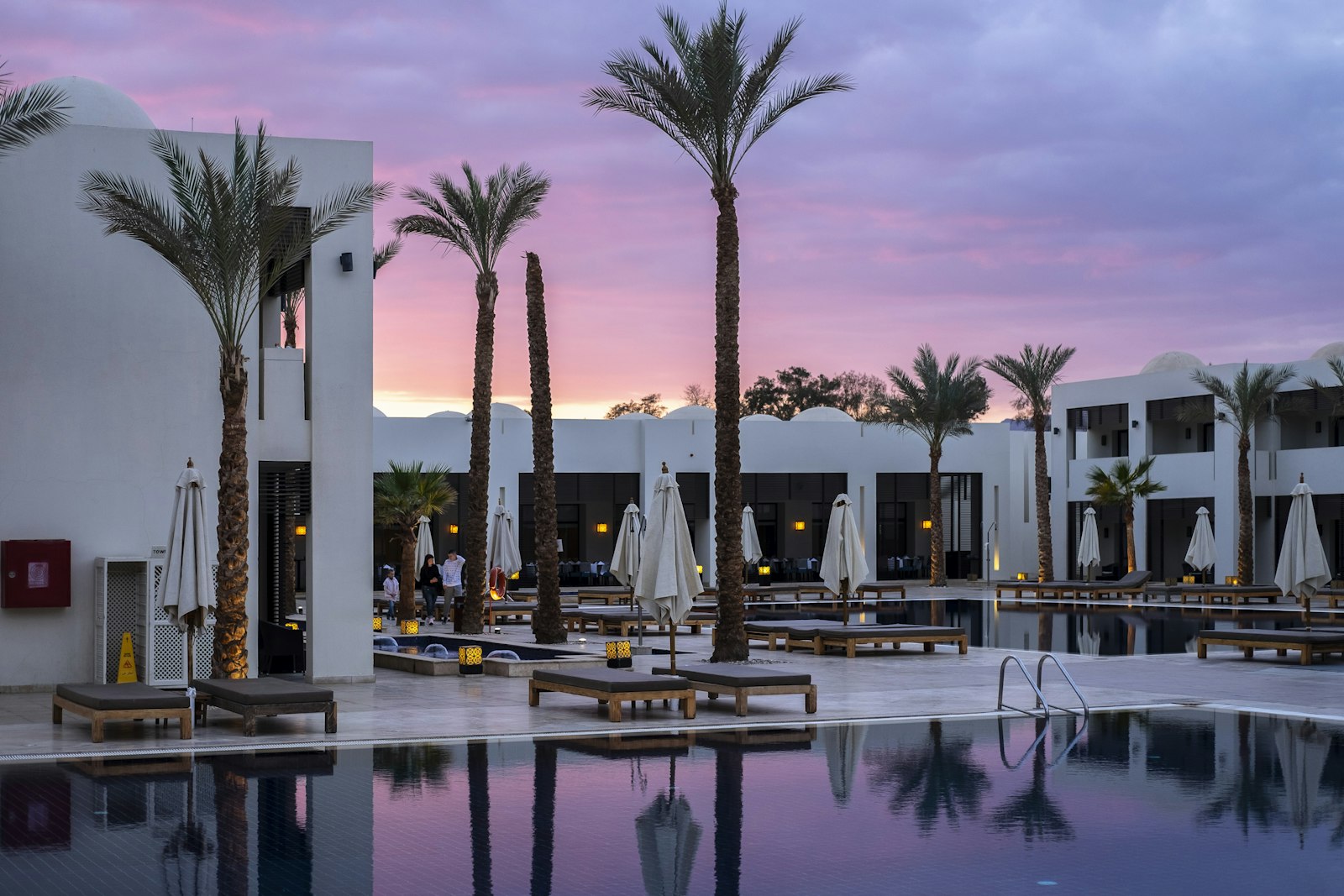 A palm-lined pool at sunset, the kind of scene a visitor wants to linger inside